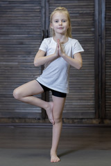 Fototapeta premium girl child doing exercises doing yoga on a Mat in the Studio or at home . the child is engaged in physical education stretching and training