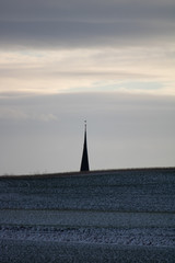 Fototapeta premium the roof of a church behind a hill at dusk