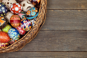 Still life with Easter egg decorated with Easter eggs stand in a wicker basket on a wooden root...