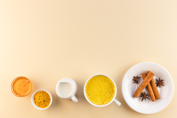 Golden milk and ingredients for its preparation on a beige background. Alternative medicine concept