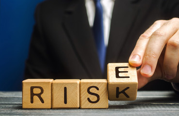 Businessman changes wooden blocks with the words Risk and Rise. Business risk management and growth...