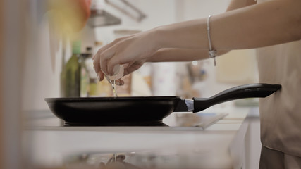 girl breaks eggs in a pan