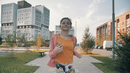 Girl on a morning jog listening to music. She is dressed in sportswear and she runs down the sidewalk in the city