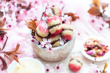 Raw vegan peaches cookies with pink spring flowers on a white table. Peach cookie for vegans. Raw food sweets.