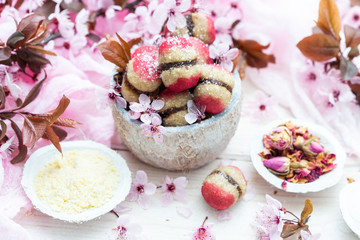 Raw vegan peaches cookies with pink spring flowers on a white table. Peach cookie for vegans. Raw food sweets.