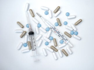 pills syringe and thermometer on white background