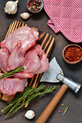 A fresh, raw rabbit with an ax and spices on a concrete background.