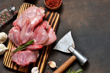 A fresh, raw rabbit with an ax and spices on a concrete background. © zefirchik06