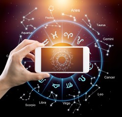 Male hand holding smart phone device with astrology illustrations