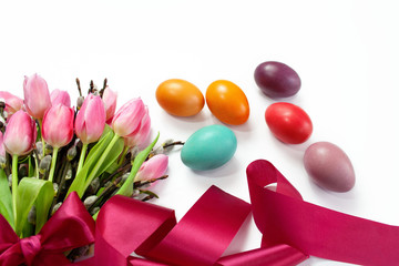 Wielkanocne tło z kolorowymi pisankami i bukietem z tulipanów i bazi przewiązanym wstążką
