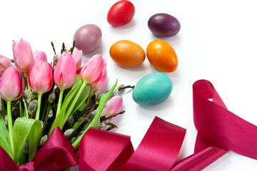 Easter background with colorful Easter eggs and a bouquet of tulips and catkins tied with a ribbon