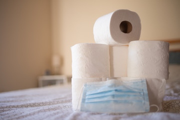 Background with toilet paper, and a mask. Coronavirus, panic. Buying toilet paper.
