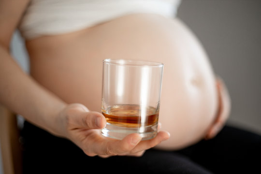 pregnant woman with whiskey glass in the right hand