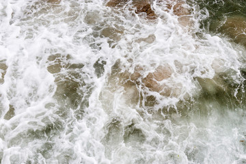 Top view texture waves, foaming and splashing in the ocean, sunny day.  Beautiful tropical sea in summer season image by aerial view. Abstract sea background. Ocean waves close-up.
