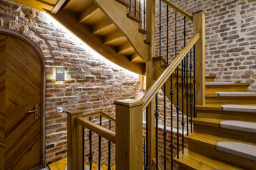 Modrrn loft interior of entrance in multi-storey apartment building. Brick wall. Wooden staircase.