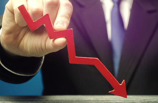 Businessman holds a red down arrow. The concept of reducing profits and income. Recession and the financial crisis. Capital outflow. Forecast