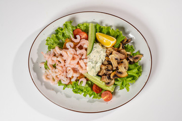 Tasty dinner. Delicious food on the white plate isolated on white. Prawns and fried mushrooms. Close-up.