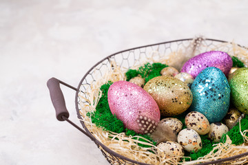Easter composition with colorful Easter eggs on moss in basket. Greeting Easter card for spring holiday. Top view, copy space