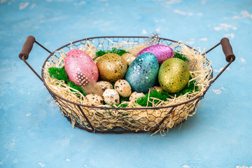 Easter composition with colorful Easter eggs on moss in basket. Greeting Easter card for spring holiday. Top view