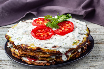 Zucchini cake with tomatoes and fresh parsley on white wooden background.