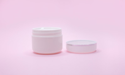 White cosmetic jar on pink background