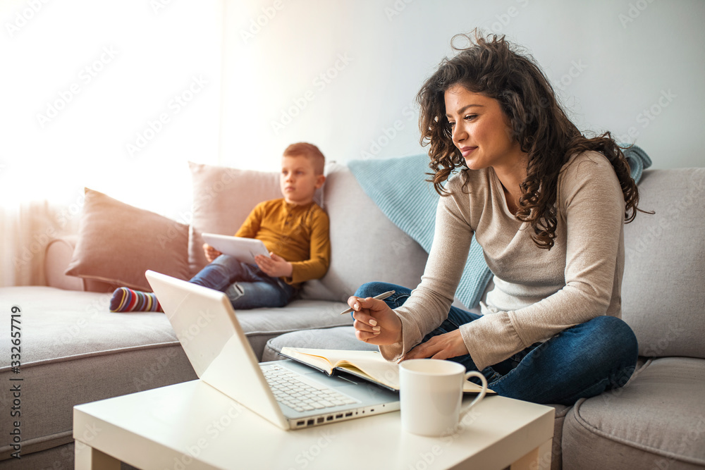 Wall mural millennial generation mother working from home with small children while in quarantine isolation dur