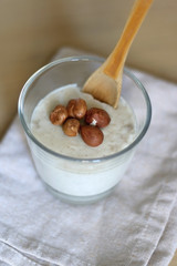 Glass of vanilla pudding with hazelnut topping and wooden spoon. Selective focus.