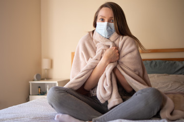 Girl with fever and symptoms of coronavirus, covered with a blanket. Quarantine, home privacy, self-isolation