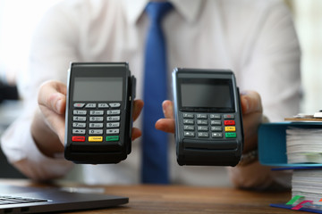 Close-up of person hands holding two different terminals for contactless payment. Seller proposing for choice various variants. Modern technology concept