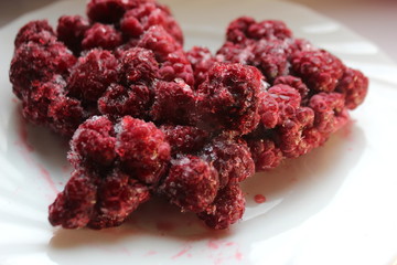 Frozen raspberries on a white background. Steam from frozen raspberries. Frozen fresh berries. Frozen berries of raspberries, covered with hoarfrost. Close-up.