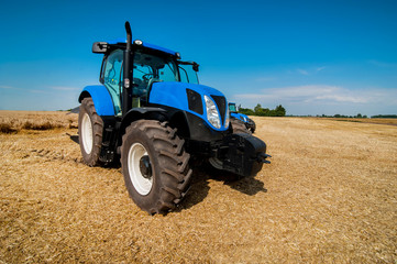 New blue tractor working on the field, modern agricultural transport