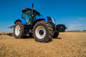 Obraz premium New blue tractor working on the field, modern agricultural vehicle