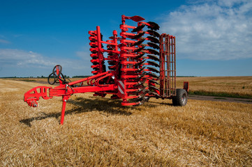 Red harrow folded for transportation for cultivating the land. Harrow on the field and beautiful...