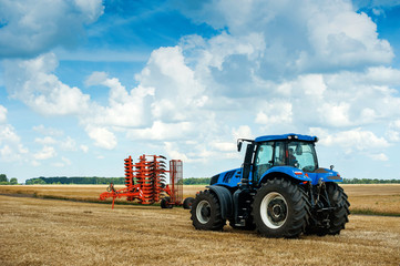 blue tractor and red harrows, arable land, field preparation
