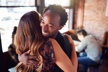 Couple Greeting Each Other With Hug As They Meet In Coffee Shop