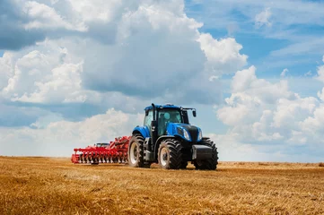 Foto op Plexiglas blauwe tractor in het veld, werk met landbouwmachines, veld en prachtige lucht © pavlobaliukh