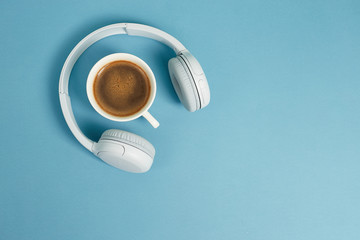 Music or podcast background with headphones and cup of coffee on pink background, flat lay. Top view, flat lay