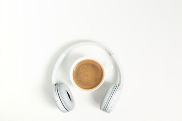Music or podcast background with headphones and cup of coffee on pink background, flat lay. Top view, flat lay