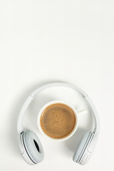 Music or podcast background with headphones and cup of coffee on pink background, flat lay. Top view, flat lay