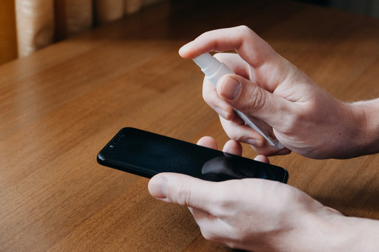 How to properly clean and disinfect your smartphone with oleophobic coating. Cleaning mobile phone to eliminate germs, coronavirus Covid-19. Man hands cleaning smartphone