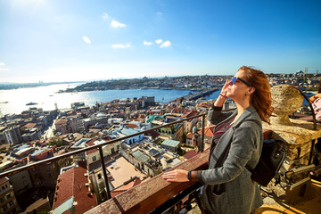Fototapeta na wymiar A beautiful girl tourist enjoying the view of historical center of Istanbul from the top of the Galata Tower
