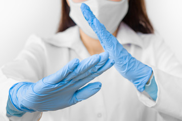 Stop SARS-CoV, SARSCoV, virus 2020 , MERS-CoV ,chinese virus COVID-19. Closeup womans hands in blue medical gloves show STOP sign to illness. Doctor wearing protection face mask against coronavirus.