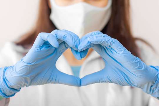 Stop SARSCoV, MERS-CoV ,chinese Virus COVID-19. Closeup Womens Hand In Blue Medical Gloves Show Heart Sign. Concept Of Protection Against HIV. Doctor In Blue Medical Gloves And Protective Mask.