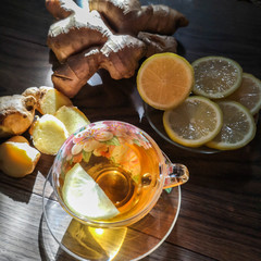 Cup of ginger tea with lemon and honey on a wooden background, top view.