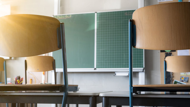 CORONAVIRUS - School Closed - Empty Classroom With High Chairs And Empty Green Blackboard / Chalkboard