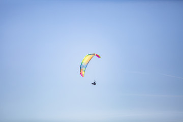Skydiver with a colorful canopy of a parachute on the background a blue sky