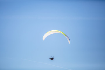Skydiver with a colorful canopy of a parachute on the background a blue sky