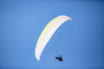 Skydiver with a colorful canopy of a parachute on the background a blue sky