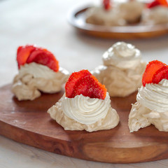 the process of creating Pavlova dessert, decorating the meringue with strawberries