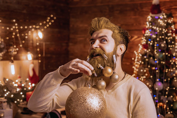 Portrait of handsome Santa man indoors with Christmas ball, gold bauble. Theme Christmas holidays and winter new year. Santa father with a white beard posing on the Christmas wooden background.